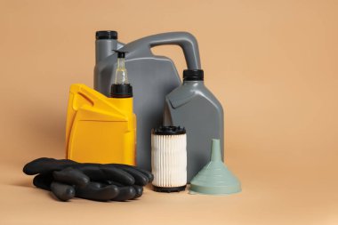 Plastik kaplarda motor yağı, filtre, bej arka planda eldiven ve huni, metin için boşluk