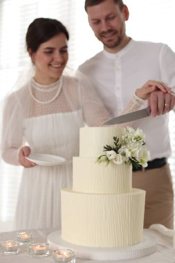 Evli çift evde bıçakla düğün pastası kesiyor, seçici bir odak noktası var.