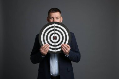 Hedef alınıyor. Gri arka planda dart tahtası olan adam.