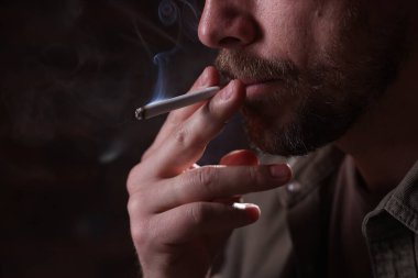 Arka planda sigara içen adam, yakın plan.