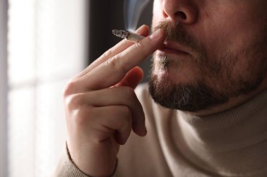 Arka planda sigara içen adam, yakın plan.