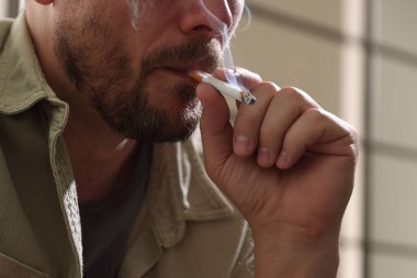 Arka planda sigara içen adam, yakın plan.