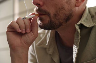 Arka planda sigara içen adam, yakın plan.