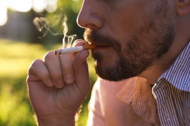 Arka planda sigara içen adam, yakın plan.