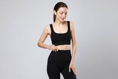 Gri arka planda düz göbekli güzel bir kadın.