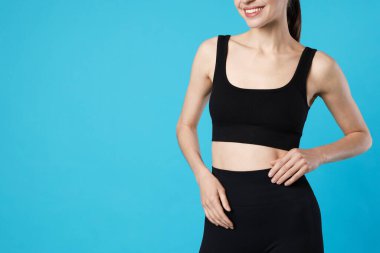 Açık mavi arka planda düz göbekli güzel bir kadın, yakın plan. Metin için boşluk