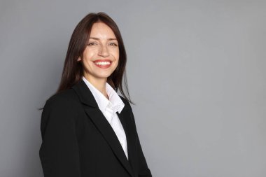 Gri arka planda takım elbiseli mutlu kadın, mesaj için boşluk