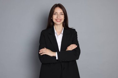 Gri arka planda takım elbiseli mutlu kadın