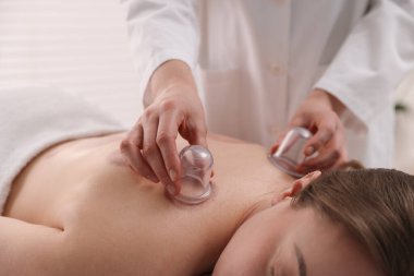 Terapist, kaplıca salonundaki hastaya kupa tedavisi uyguluyor.