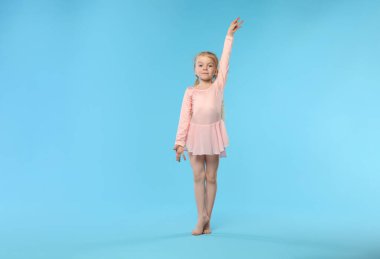 Açık mavi arka planda dans eden tatlı küçük kız.