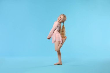 Açık mavi arka planda dans eden tatlı küçük kız.