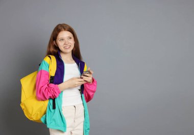 Gri arka planda akıllı telefonu olan genç bir kız. Metin için boşluk