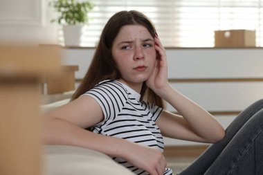 Evde yerde üzgün bir genç kız var.