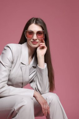 Pembe arka planda şık giyinmiş güzel bir kadının moda portresi.