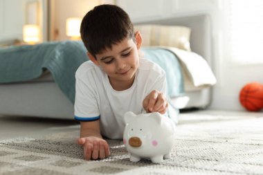 Çocuk evdeki domuz kumbarasına cep harçlığı koyuyor.