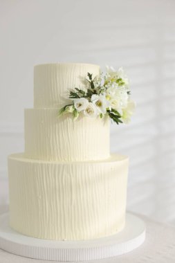 İçerideki masada çiçeklerle süslenmiş nefis düğün pastası.