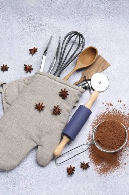 Fırın eldiveninde farklı mutfak gereçleri, kakao tozu ve anason yıldızları ışık masasında düz uzanıyordu.