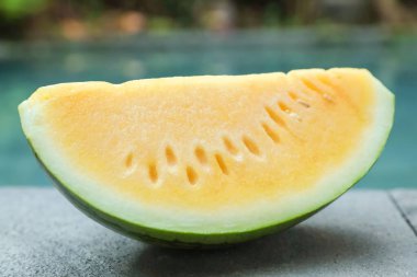 Dışarıdaki yüzme havuzunun yanında taş yüzeyde leziz bir karpuz dilimi, yakın plan.