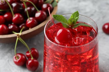 Buzlu vişneli gazoz, böğürtlen ve nane. Gri desenli masa, yakın plan.