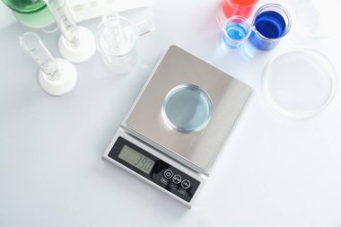 Beyaz masa üzerinde Petri kabı ve diğer laboratuvar camları ile ölçeklendir.
