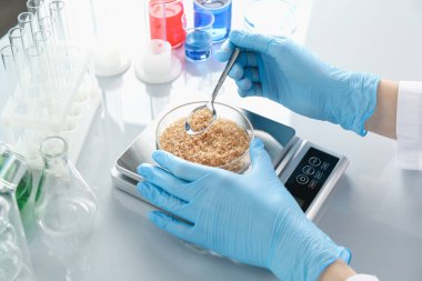 Petri kabını tartan bilimadamı beyaz ayna masasında, yakın plan.