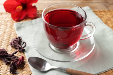 Cam bardakta leziz amber çayı, kuru roselle sepals ve masada kaşık, yakın plan.