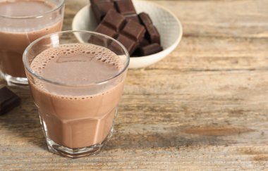 Bardakta çikolatalı süt ve ahşap masada parçalar, yakın plan. Metin için boşluk