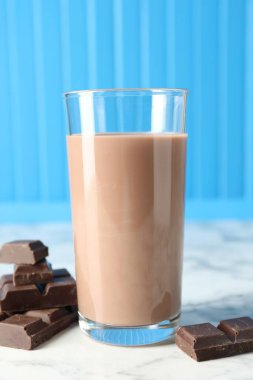 Bardakta çikolatalı süt ve beyaz mermer masada malzeme, yakın plan.