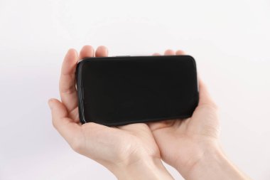 Woman holding smartphone with blank screen on white background, closeup. Mockup for design