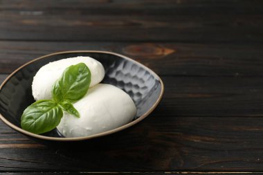 Ahşap masadaki fesleğen ve mozzarella peyniri parçaları, yakın plan. Metin için boşluk