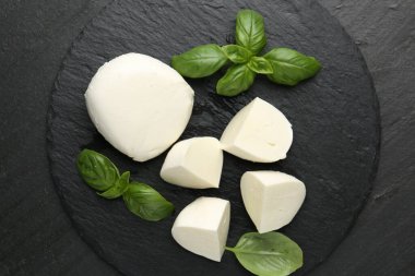 Lezzetli mozzarella peyniri ve fesleğen parçaları koyu dokulu masa, üst manzara.