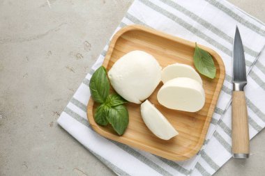 Lezzetli mozzarella peyniri parçaları, fesleğen yaprakları ve bıçak gri desenli masa, üst manzara