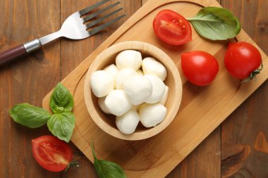 Lezzetli mozarella topları, domatesler ve fesleğenler ahşap masada, düz yatıyordu.