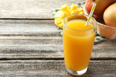 Bardakta lezzetli mango suyu ve ahşap masada taze meyveler, yakın plan. Metin için boşluk