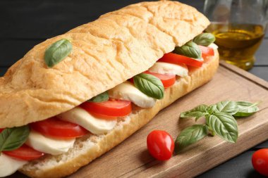 Mozarella peynirli, domatesli, fesleğenli, siyah ahşap masa, yakın plan.