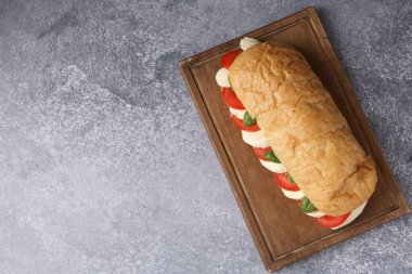 Mozarella peynirli, domatesli, fesleğenli, gri desenli masa manzaralı lezzetli bir sandviç. Metin için boşluk