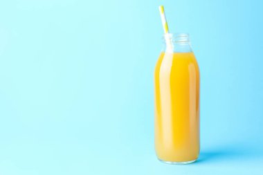 Açık mavi zemin üzerinde cam şişe içinde lezzetli mango suyu, metin için yer