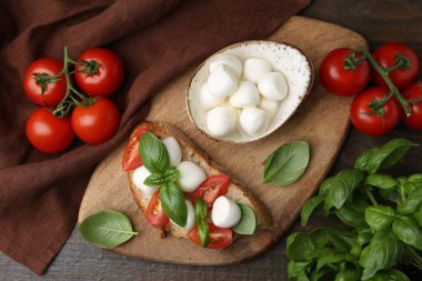 Peynirli, domatesli, ahşap masada fesleğenli lezzetli bir sandviç.