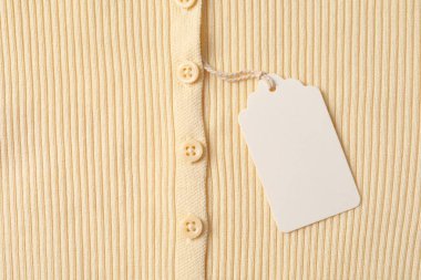 Karton etiketli bej giysi, üst görünüm