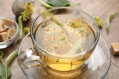 Taze ıhlamur çayı, şeker küpleri ve çiçekler ahşap masada, yakın plan.