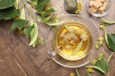 Fincanda taze ıhlamur çayı, şeker küpleri ve tahta masada çiçekler, düz uzanma. Metin için boşluk