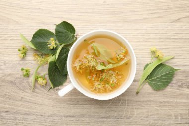 Taze ıhlamur çayı fincanda ve çiçekler ahşap masada, düz yerde.