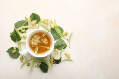 Taze ıhlamur çayı fincanda, çiçekler beyaz masada, düz yerde. Metin için boşluk