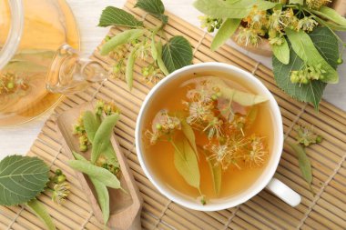 Taze ıhlamur çayı, çaydanlık ve çiçekler beyaz ahşap masada, düz uzanmış