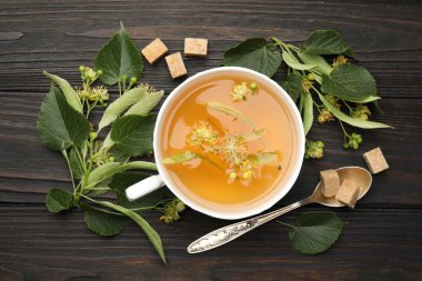 Taze ıhlamur çayı, şeker küpleri ve çiçekler koyu ahşap masada, düz uzanmış