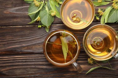 Taze ıhlamur çayı fincanda ve çiçekler ahşap masada, düz yerde. Metin için boşluk