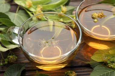 Fincanlarda taze ıhlamur çayı ve ahşap masada çiçekler, yakın plan.