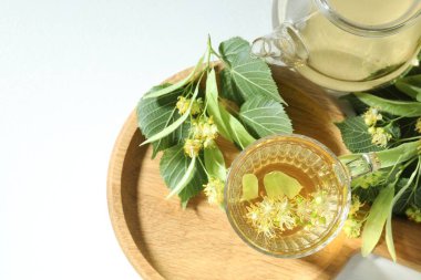 Lezzetli ıhlamur çayı, yapraklar ve çiçekler ışık masasında.