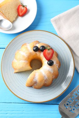 Pudra şekerli ve böğürtlenli lezzetli kek açık mavi ahşap masa, düz uzanmış