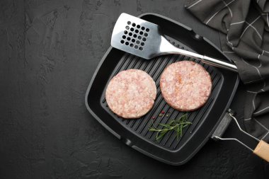 Hamburger ve baharatlar için taze çiğ köfteler, siyah masada, üst tarafta. Metin için boşluk